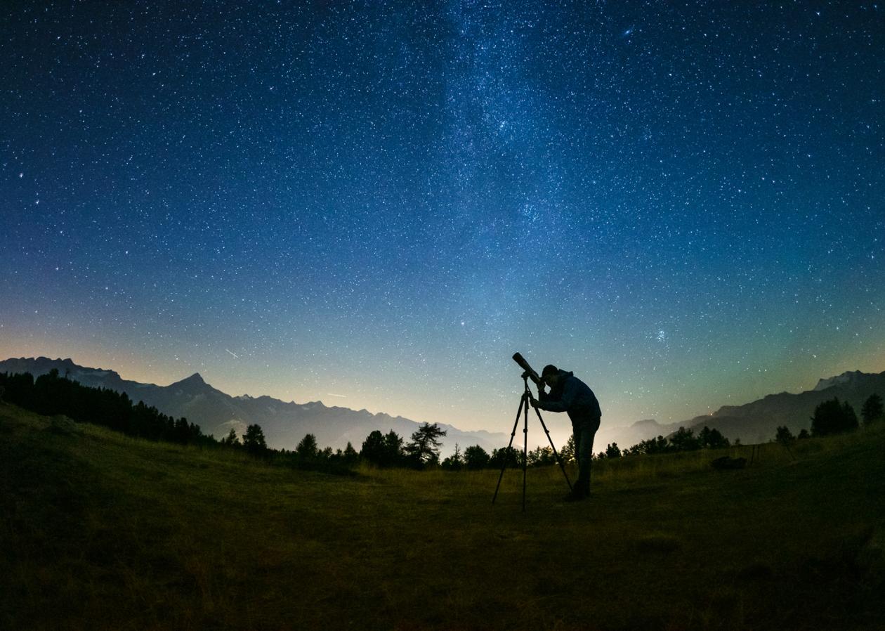 Sterngucker Peter Salzmann schaut durch ein Fernrohr in den Nachthimmel.
