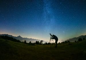 Sterngucker Peter Salzmann schaut durch ein Fernrohr in den Nachthimmel.