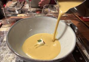 Sellerie-Suppe wird am Tisch in den Teller geschüttet.