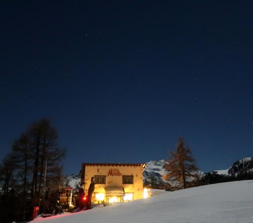 Kleines warmes Restaurant Moosalp vor der Mischabelgruppe in kühler Nacht.